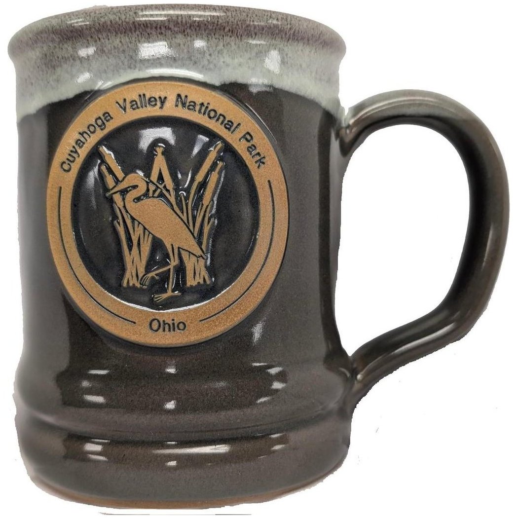 A front view of the Deneen Pottery Cuyahoga Valley National Park Mug in Forest color showing the logo and handle.