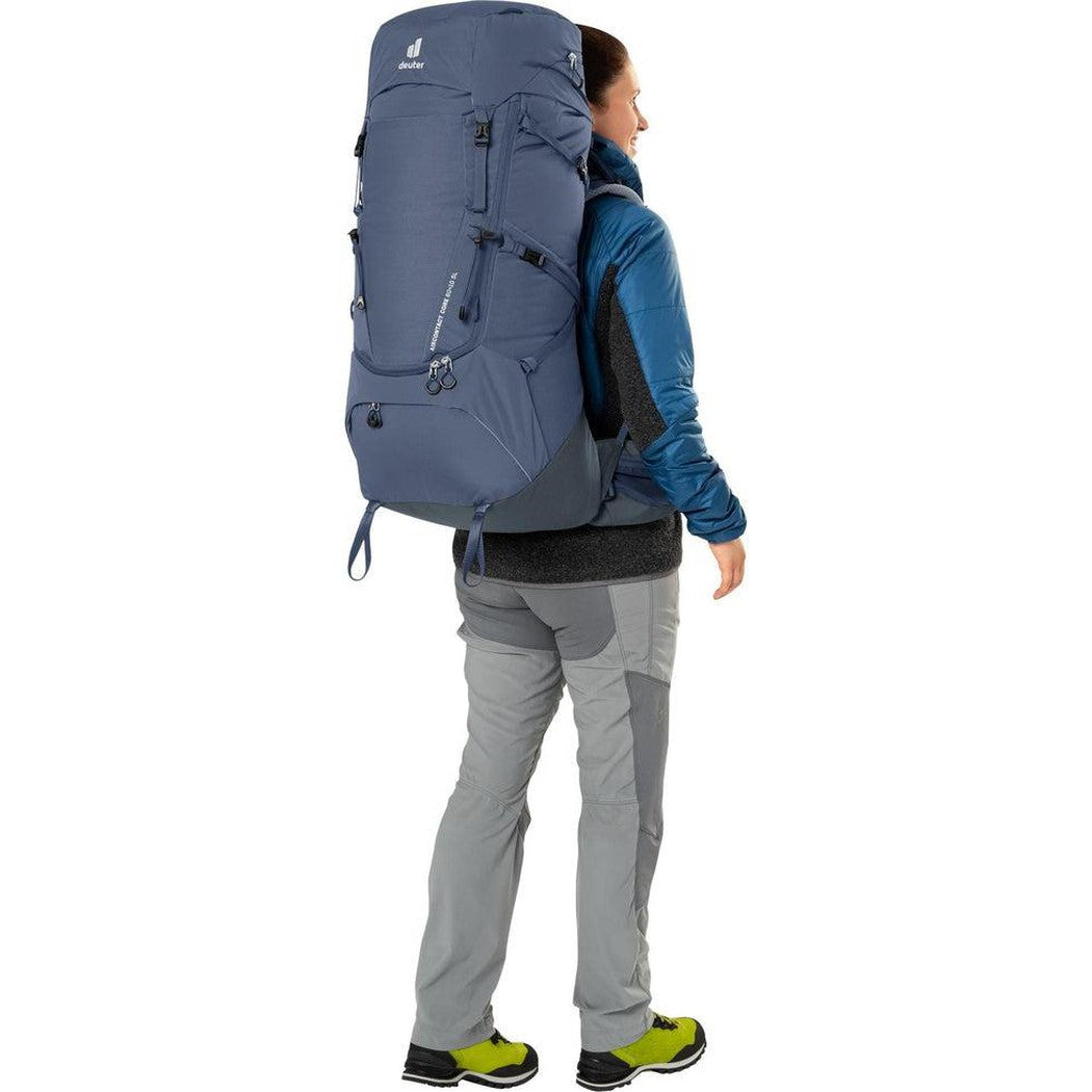 Side view of the Deuter Aircontact Core 60 + 10 SL in Ink Graphite showing the large main compartment and a woman wearing it against a white background.