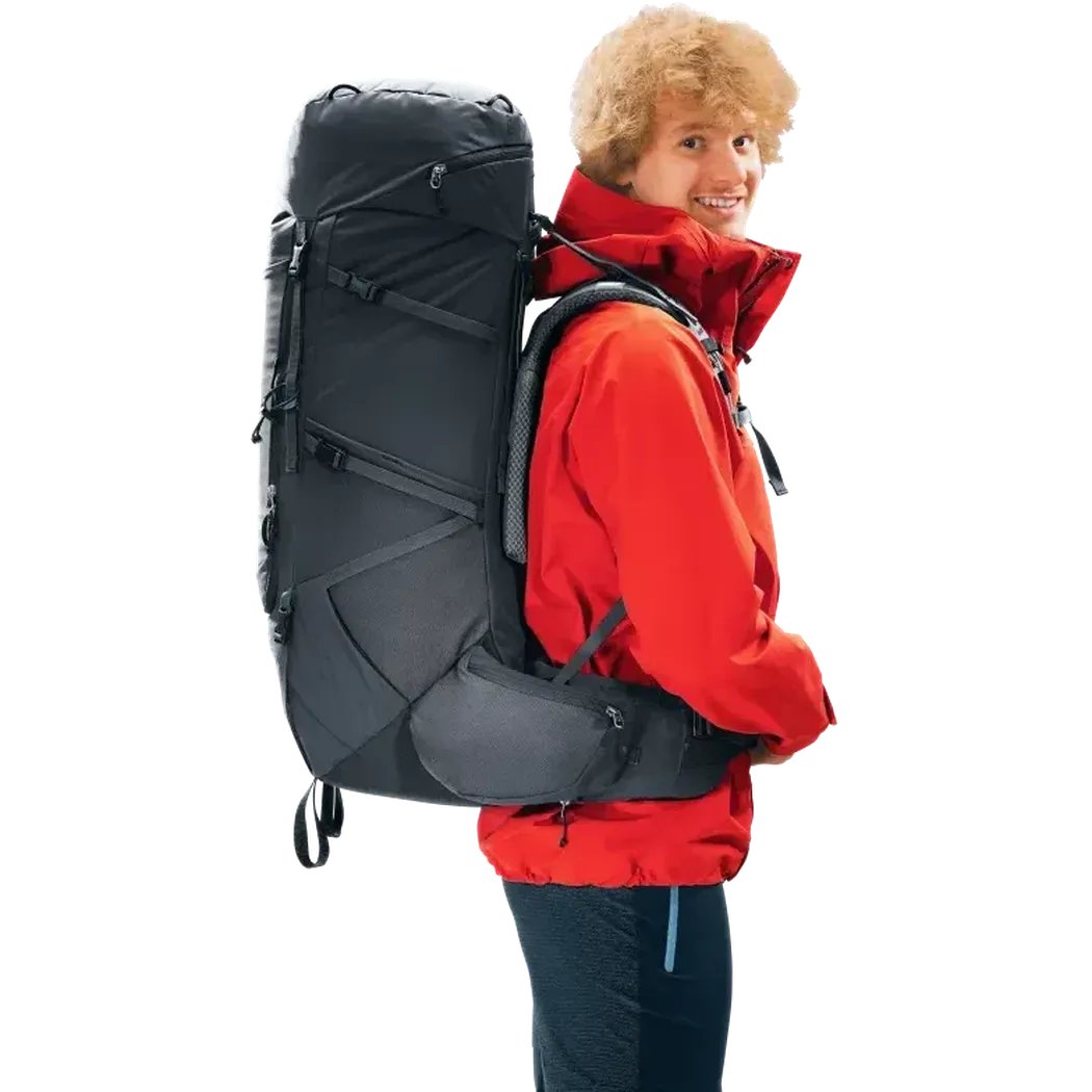 Side view of the Deuter Aircontact Core 60+10 black backpack on a model wearing a red jacket against a white background.