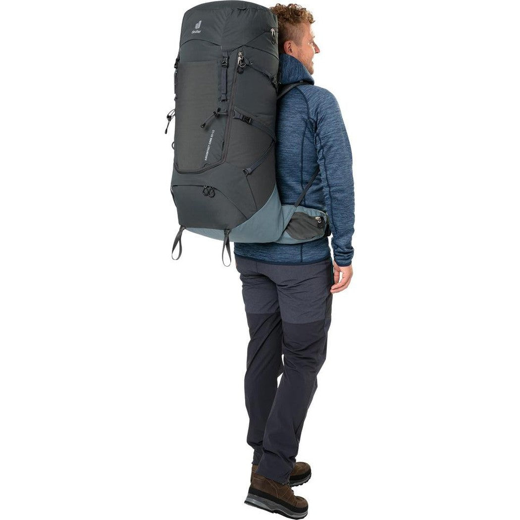 Side view of the Deuter Aircontact Core 65 + 10 in Graphite Shale showing the large main compartment and a model wearing it against a white background.