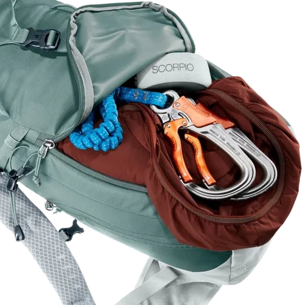 Side view of the Deuter Trail 16 SL in Teal Tin showing climbing gear in the front pocket against a white background.