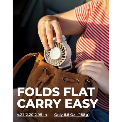 A person holds the black Diveblues Fanzy Handheld Fan over a brown bag, showing it folds flat for easy carry.
