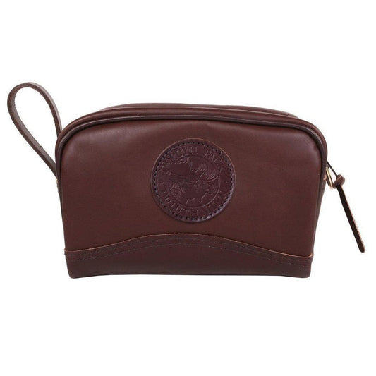 A brown smooth Duluth Pack Leather Sportsman's Kit Bag with a circular logo and zipper pull, shown from the front against a white background.
