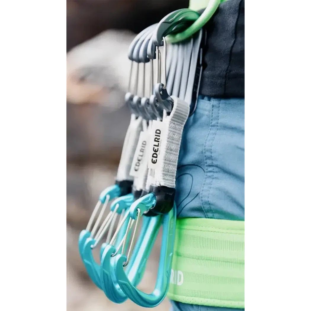 A close-up of the Edelrid Pure Wire Set Sixpack, 10cm in Slate/Icemint, showing the quickdraws attached to a green harness with blue carabiners.