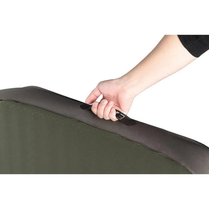 A hand grips the handle of the Morraine Exped MegaMat Auto sleeping pad against a white background.