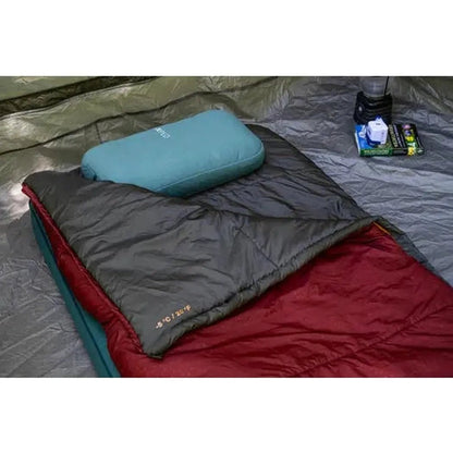 A close-up of the Burgundy Exped MegaPillow on a sleeping pad inside a tent, with camping gear nearby.