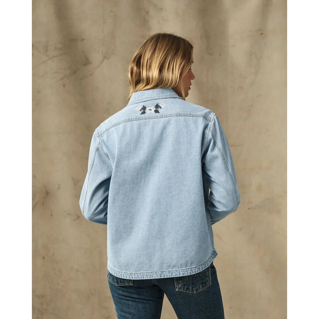 Back view of the Filson Womens Denim Shirt in Pale Indigo showing the back of the collar and two small embroidered designs on the upper back against a neutral background.