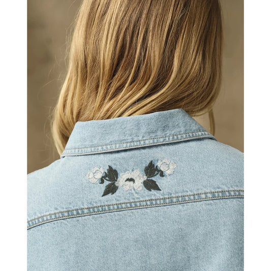 Back view of the Filson Womens Denim Shirt in Pale Indigo showing the floral embroidery on the collar against a neutral background.