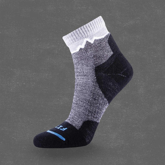 A side view of the FITS Light Cushion Hiker Quarter - Crestone sock in Charcoal with a gray midsection and white cuff against a dark gray background.