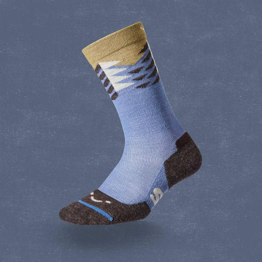 Side view of the FITS Light Hiker Crew - Stand Fir socks in Steel Blue with a charcoal heel and toe, against a blue background.