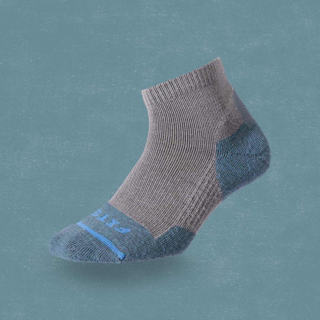 Side view of the FITS Light Hiker Quarter in Coal showing the quarter length and reinforced heel and toe against a solid teal background.