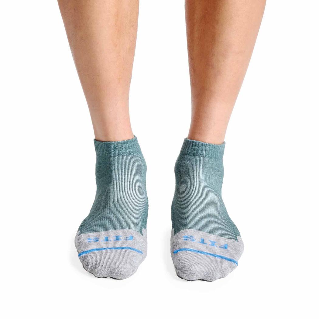 A front view of the FITS Light Hiker Quarter socks in Coal color on a person's feet against a white background.