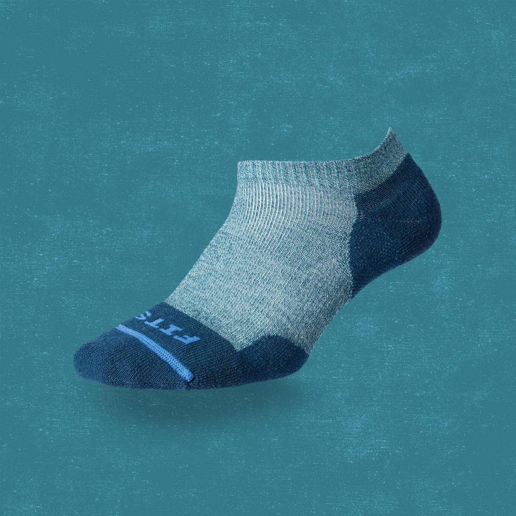 A side view of the FITS Light Runner Low socks in Juno color against a teal background.