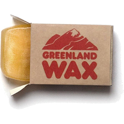 A side view of the Fjallraven Greenland Wax Travel Pack showing the yellow wax and brown cardboard packaging with red text and mountain graphic against a white background.