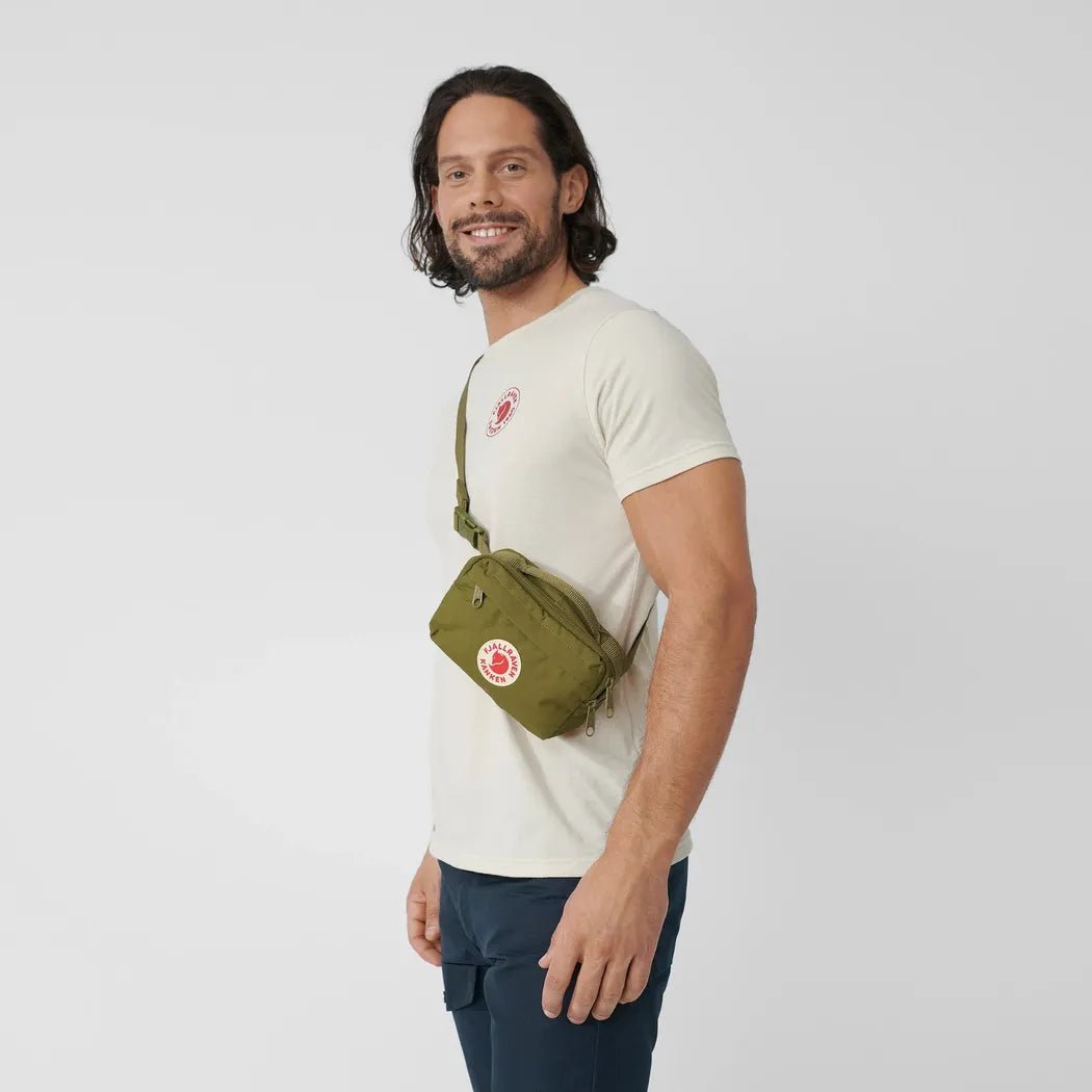 Side view of the Fjallraven Kanken Hip Pack in Green on a model against a white background.