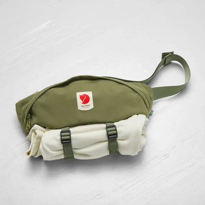 A side view of the Fjallraven Ulvo Hip Pack Large in Black showing the front pocket and adjustable strap against a white background.