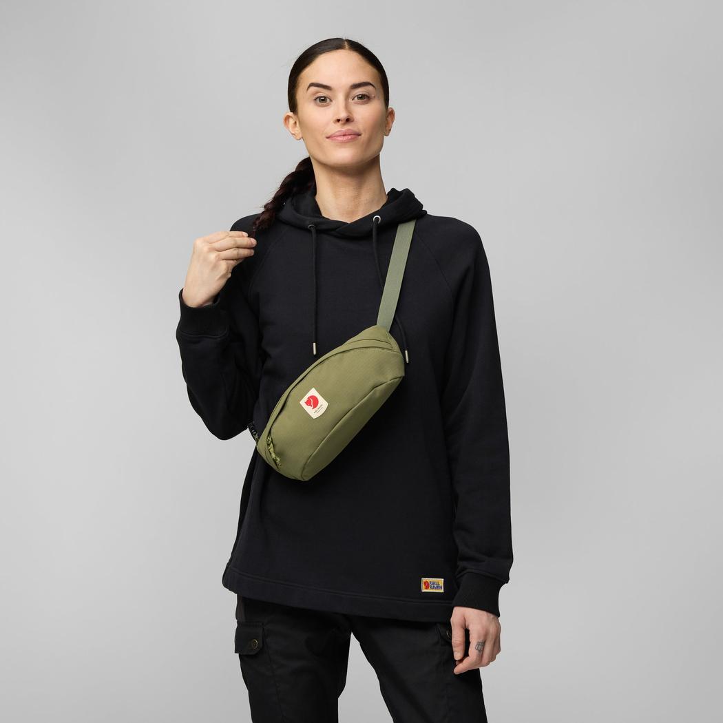 A model wears the Fjallraven Ulvo Hip Pack Medium in Black against a light gray background.