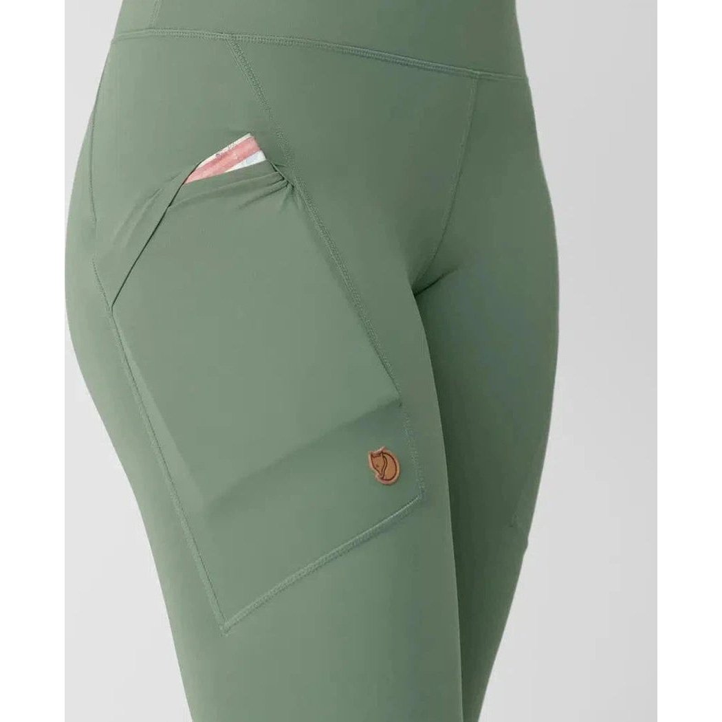 Side view of the Fjallraven Women's Abisko Tights in Patina Green showing the large front pocket with a card inside against a plain background.