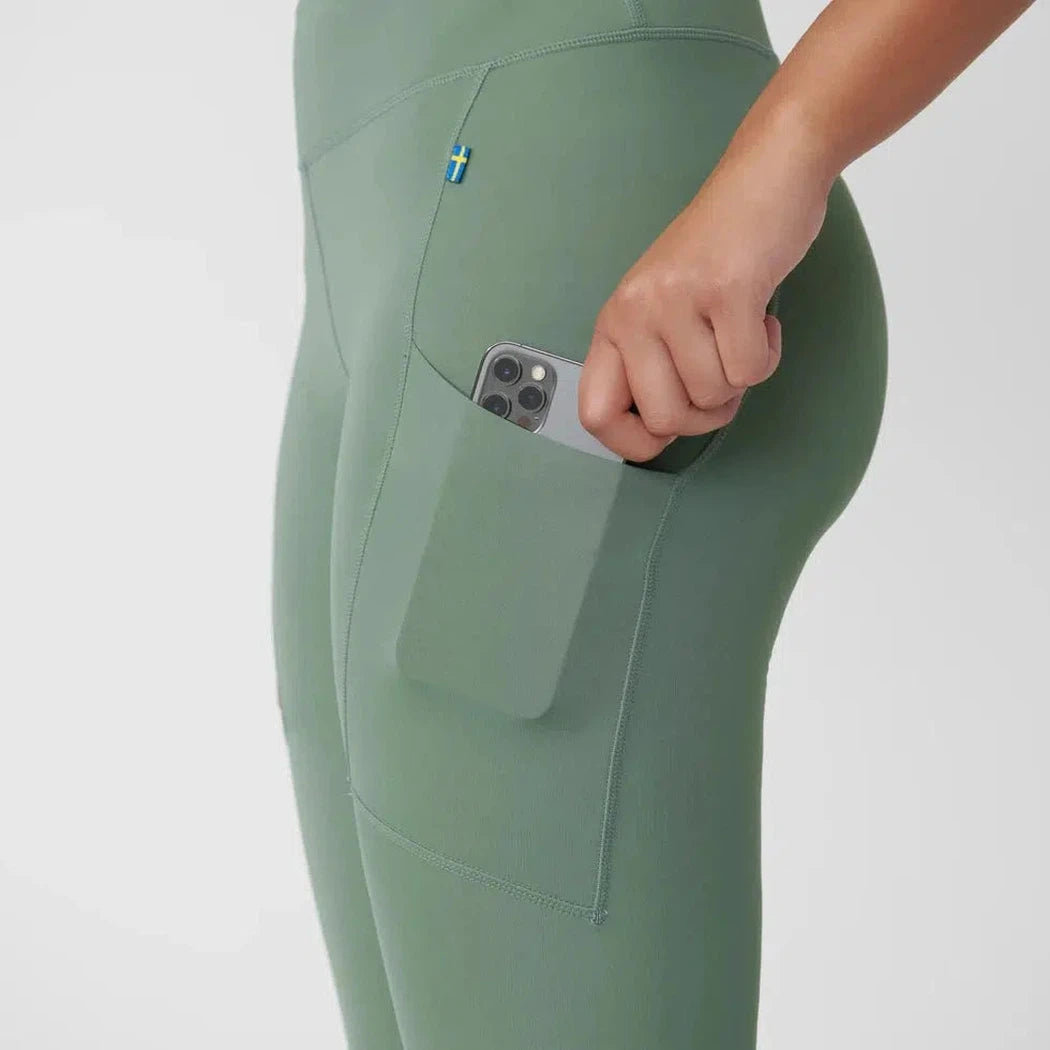 Side view of the Fjallraven Women's Abisko Tights in Patina Green showing the side pocket with a phone inside against a white background.