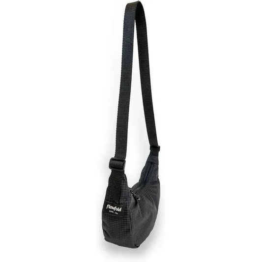 A side view of the Flowfold Mini Culter Crossbody in Coal EcoGrid with a black strap and adjustable buckle against a white background.