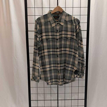 A women's Flyshacker Sample Snuggler Flannel Shirt in Ecru hangs on a wooden hanger against a grid background.
