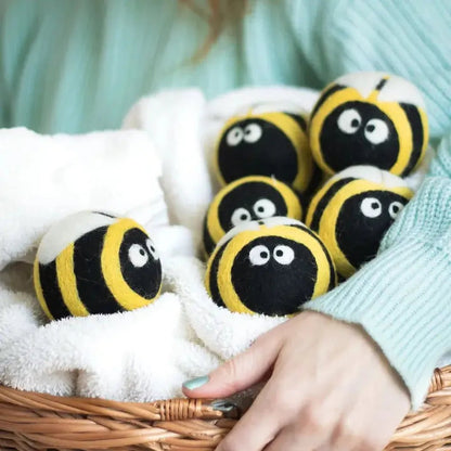 A hand holds a basket of Friendsheep Bee Trio Eco Wool Dryer Balls on a white towel.