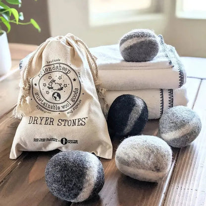 A top-down shot of handmade Friendsheep Dryer Stones Eco Wool Dryer Balls on a wooden table with folded towels in the background.