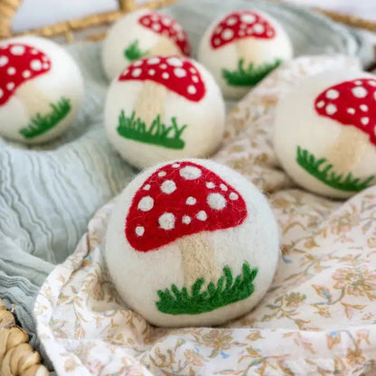 A close-up of the Friendsheep White Mushroom Trio with red and white mushrooms on a floral cloth.