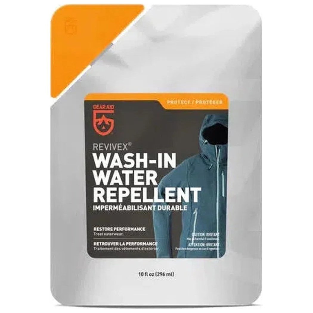 A front view of the Gear Aid Revivex Wash-In Water Repellent 10oz package showing the label and a model wearing a blue jacket.