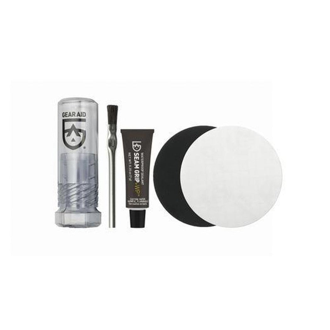 A front view of the Gear Aid Seam Grip WP Field Repair Kit with a brush, tube, and black and white pad against a white background.