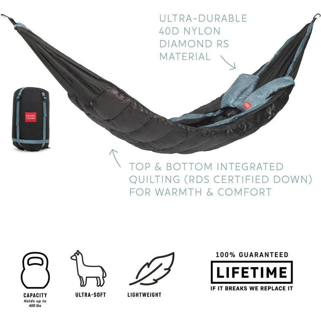 A charcoal Grand Trunk Evolution Down Hammock laid out with its compact bag visible, showing top and bottom quilting for warmth.