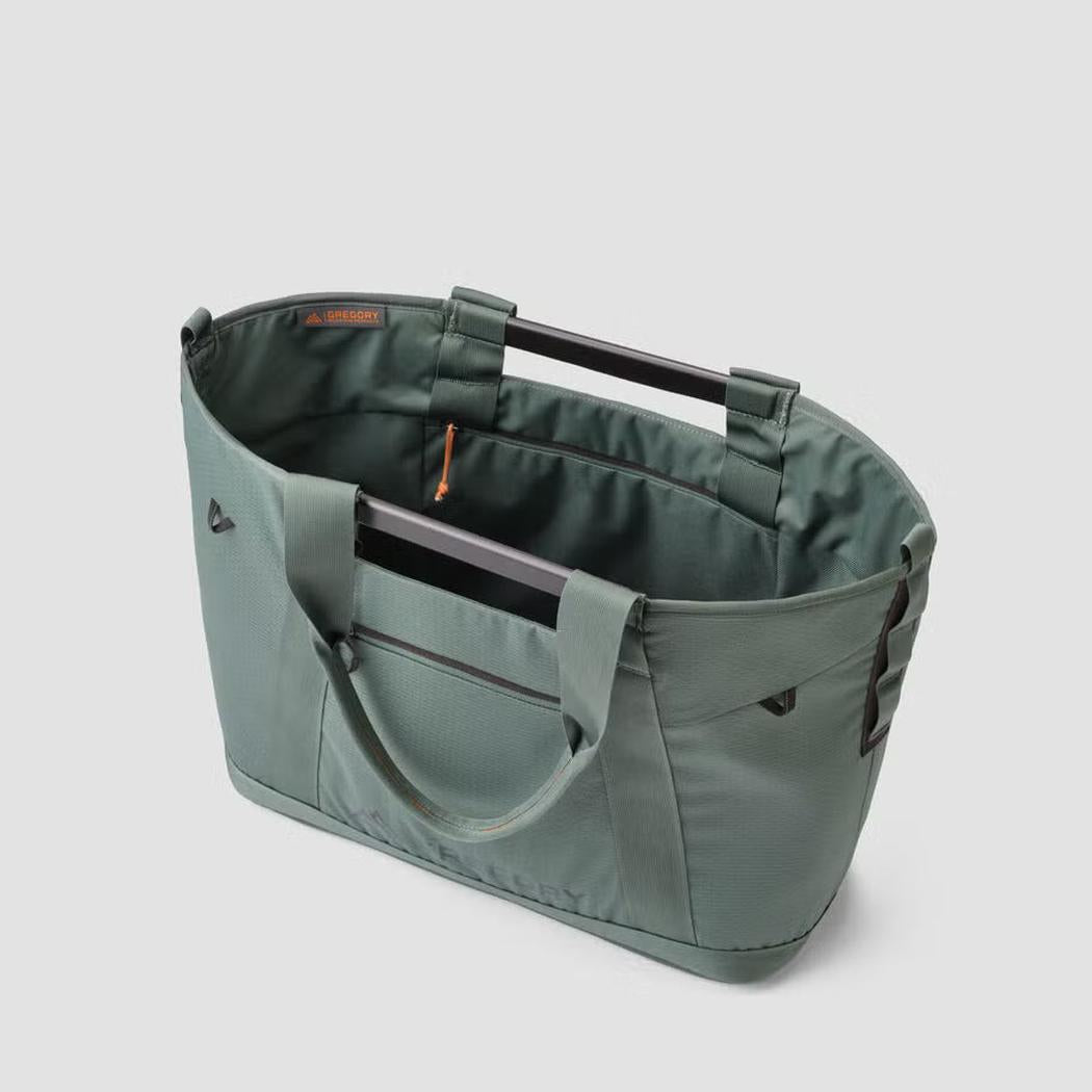 Side view of the Gregory Alpaca Utility Tote 35L in Nomad Green showing the top handles and front pocket against a light gray background.