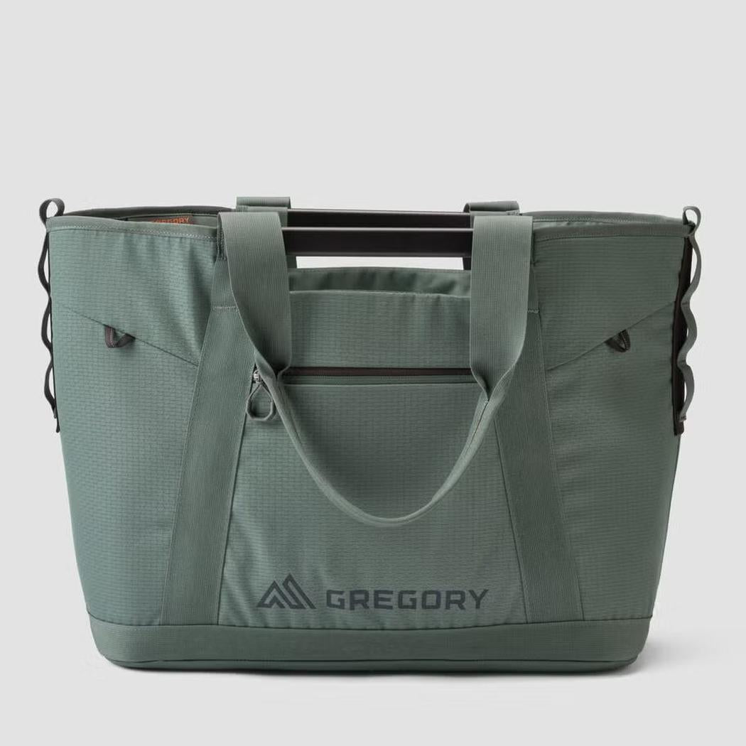 A front view of the Gregory Alpaca Utility Tote 50L in Nomad Green with a zippered pocket and logo visible against a plain background.