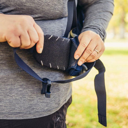 A person adjusts the Gregory Amber 68 Plus backpack with Arctic Navy straps in an outdoor setting.