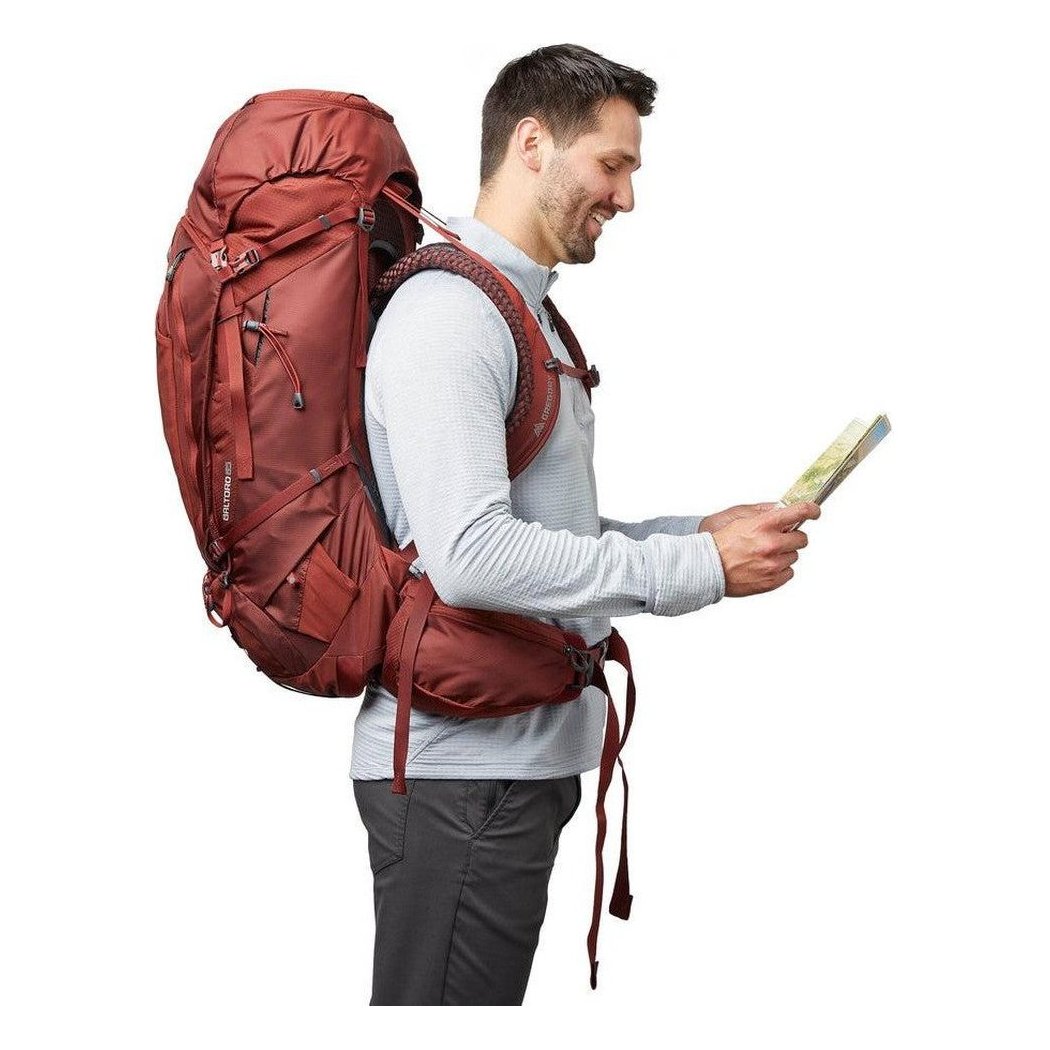 Side view of the Gregory Baltoro 65 in Brick Red showing the large main compartment and a model wearing it against a white background.