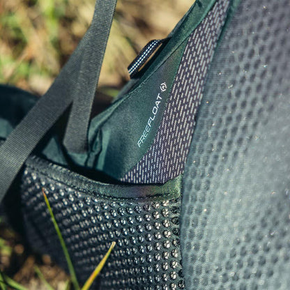 A close-up of the Gregory Paragon 70 backpack in Cascade Green, showing the REEFLOAT feature and a textured pocket against a grassy background.