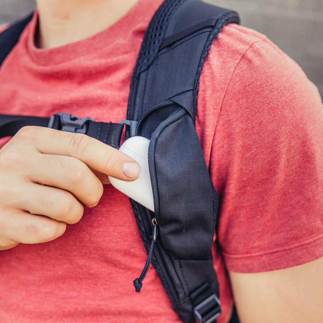 A person in a red shirt reaches into the Cabon Black Gregory Rhune 22 daypack's front pocket.