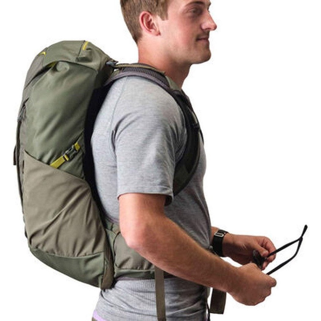 Side view of the Gregory Zulu 28 LT in Forage Green showing the large main compartment and a model wearing it against a white background.