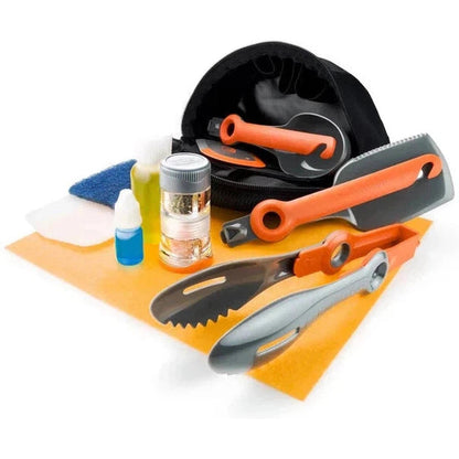 A top-down view of the GSI Outdoors Crossover Kitchen Kit with orange and gray utensils on an orange mat against a white background.
