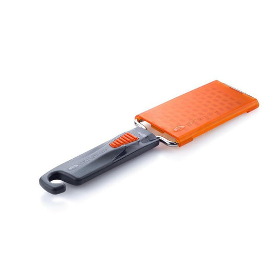 A side view of the GSI Outdoors Pack Grater with an orange grating surface and charcoal/gray handle against a white background.