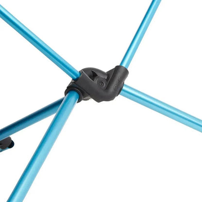 A close-up of the Helinox Table One showing the black joint and blue metal legs against a white background.