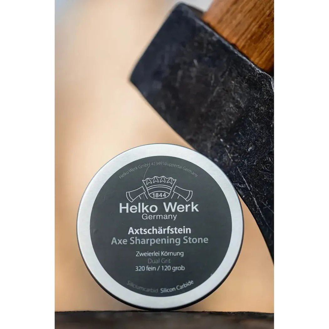 A close-up of the Helko Werk Axe Sharpening Stone next to an axe head on a light background.