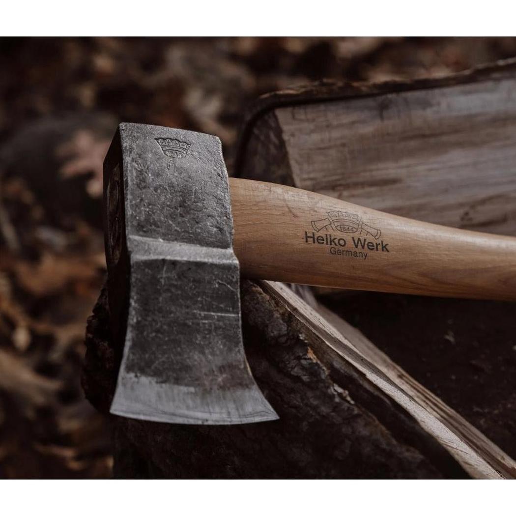 A close-up of the Helko Werk Saxon Splitter axe with its wooden handle and metal head resting on a log.