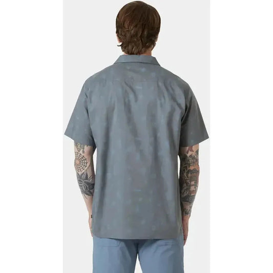 Back view of the Helly Hansen Men's Holmen Short Sleeve Shirt in Washed Navy/Pine Needle on a model with tattoos against a white background.