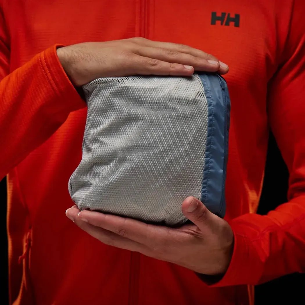 A man in an orange Helly Hansen jacket holds the Alpine Frost Helly Hansen Men's Loke Jacket 2.0 in his hands.