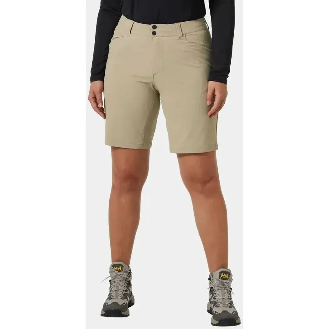 A front view of the Helly Hansen Women's Brona Softshell Shorts in Pebble, showing the model wearing them with hiking boots against a plain background.