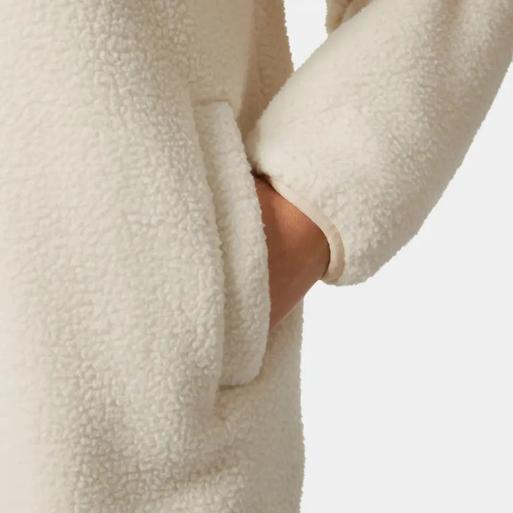 A close-up of the Helly Hansen Women's Maud Pile Jacket in Cream showing the front pocket and a model's arm against a white background.