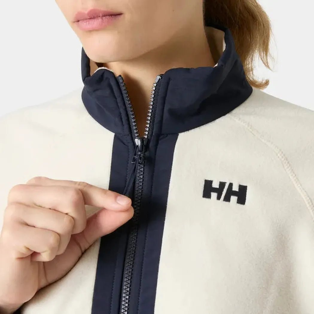 A close-up of the Helly Hansen Women’s Rig Fleece Jacket in Cream showing the front zipper and logo on a model against a plain background.