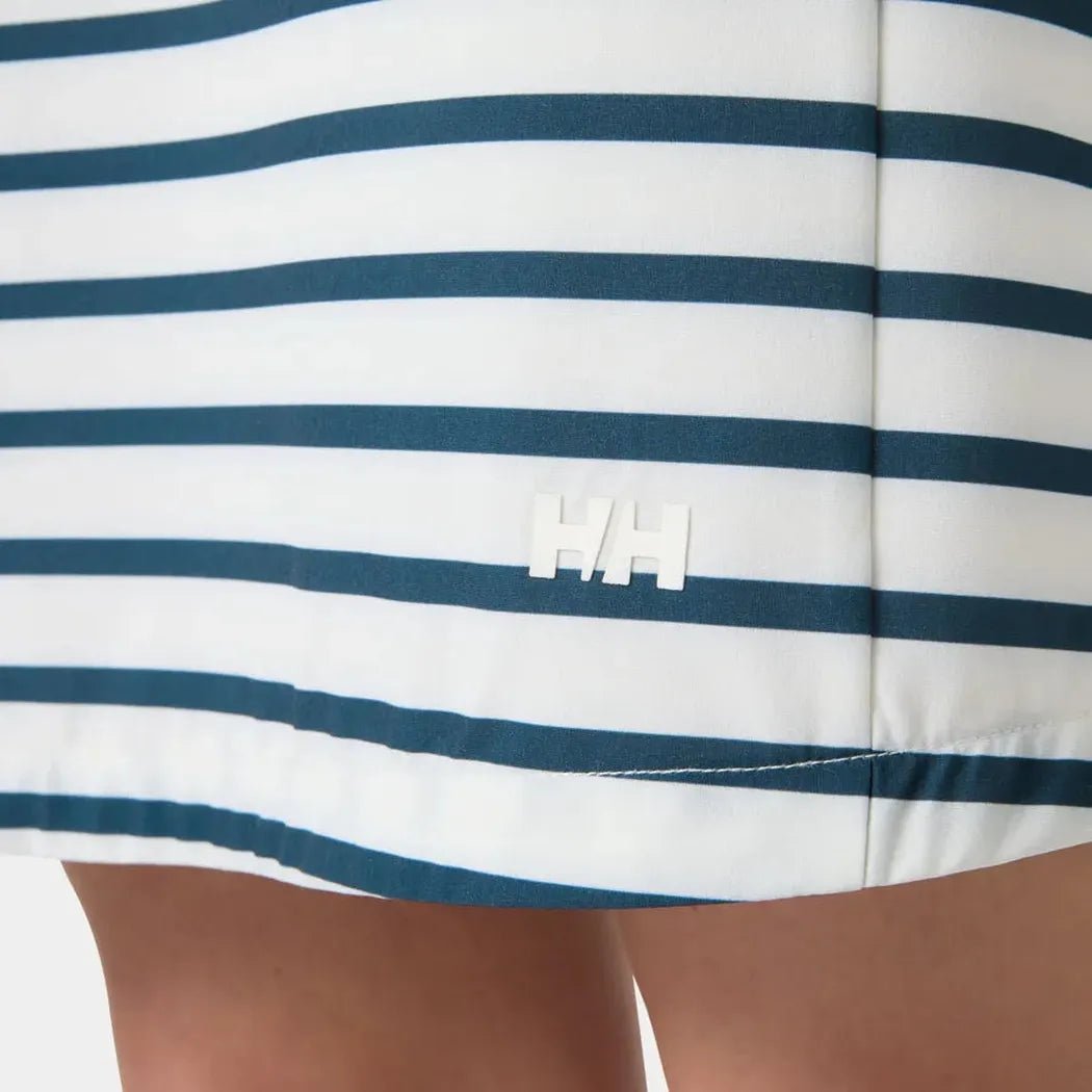 A close-up of the Helly Hansen Women's Thalia Shift Dress in White/Navy showing the brand logo and stitching on a model's lower body.
