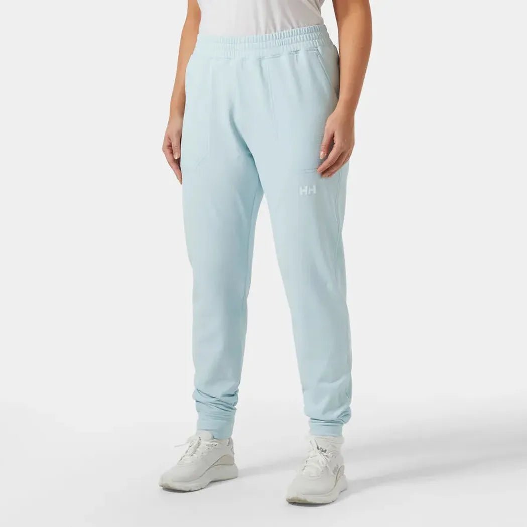 A front view of the Helly Hansen Women's Versalite Fleece Pant in Barely Blue, showing the elastic waistband and cuffs, with a model wearing white sneakers against a plain white background.